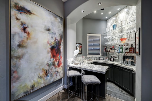 bar with dark tile flooring, gray cabinets, and light stone counters