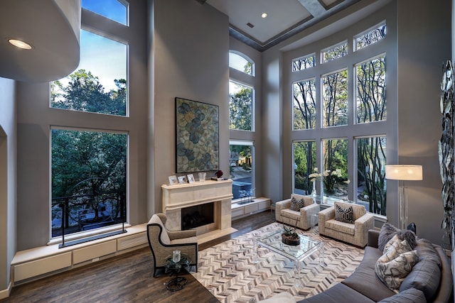 living room with coffered ceiling, a high ceiling, and hardwood / wood-style flooring