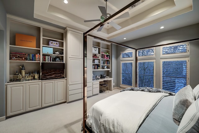 carpeted bedroom featuring a tray ceiling and ceiling fan