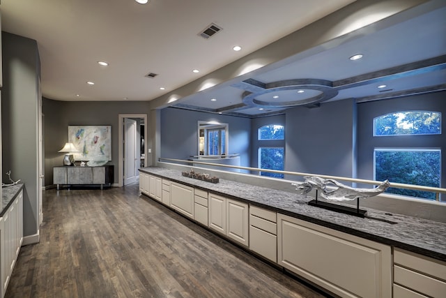 kitchen with beamed ceiling, dark hardwood / wood-style floors, white cabinetry, and dark stone countertops