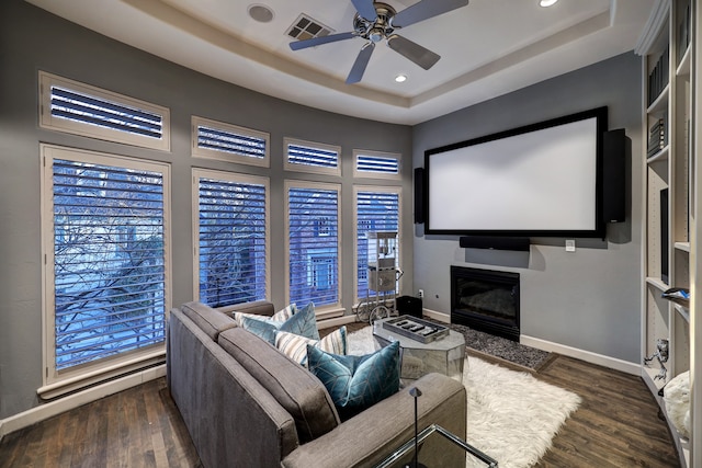 cinema featuring dark hardwood / wood-style flooring, ceiling fan, and a raised ceiling