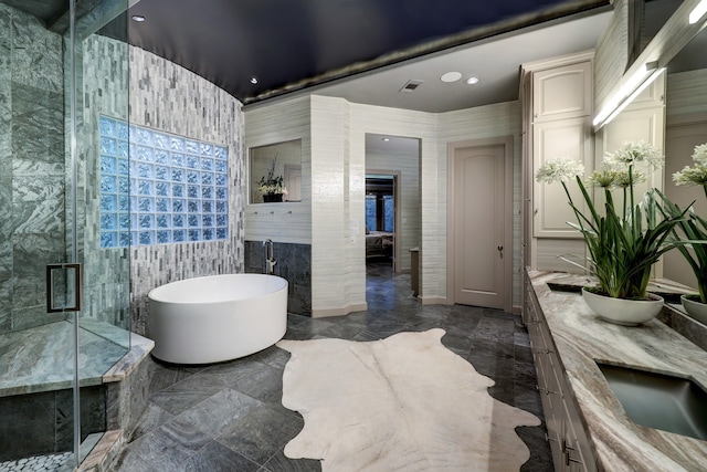 bathroom featuring tile walls, shower with separate bathtub, tile floors, and dual vanity