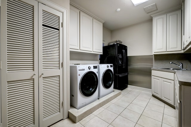 clothes washing area featuring washing machine and dryer, cabinets, sink, and light tile flooring