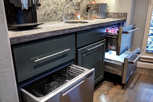 kitchen featuring dark stone counters, dark wood-type flooring, and sink