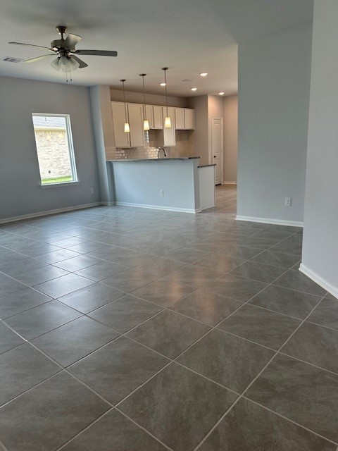 unfurnished living room with dark tile patterned floors and ceiling fan