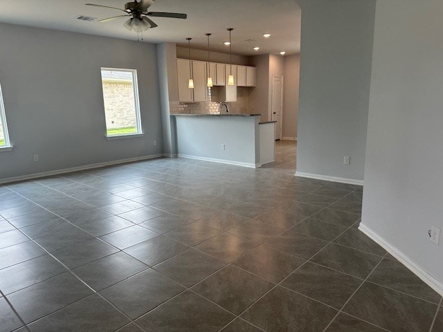 unfurnished living room with dark tile patterned floors, sink, and ceiling fan