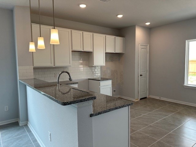 kitchen with white cabinetry, tasteful backsplash, decorative light fixtures, and kitchen peninsula