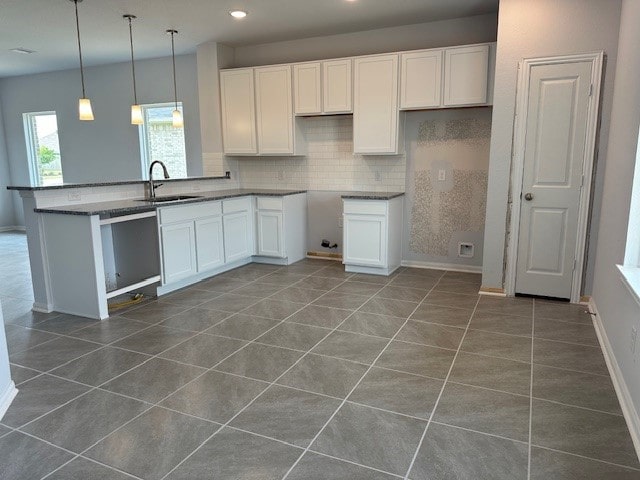 kitchen featuring dark tile patterned floors, sink, white cabinets, and pendant lighting