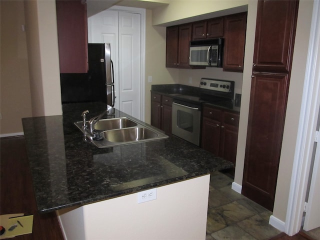 kitchen featuring appliances with stainless steel finishes, sink, dark stone counters, and dark tile floors