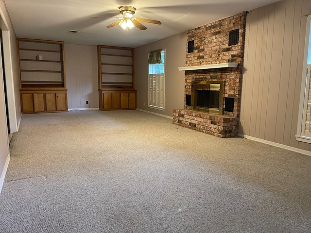 unfurnished living room featuring brick wall, carpet, ceiling fan, and a fireplace