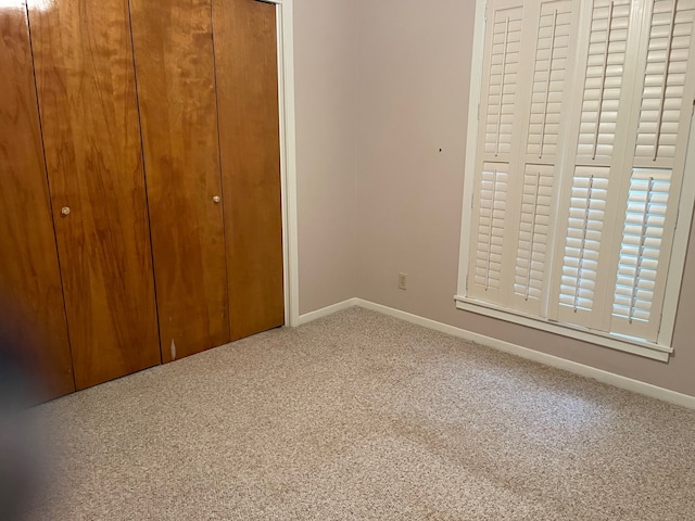 unfurnished bedroom with a closet, multiple windows, and carpet floors