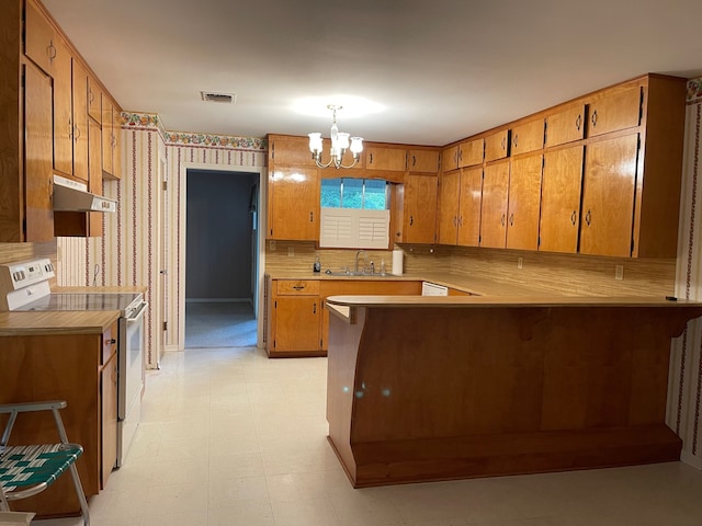 kitchen with kitchen peninsula, white range oven, backsplash, pendant lighting, and a chandelier