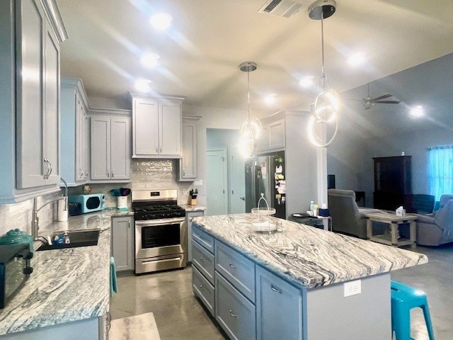 kitchen featuring stainless steel appliances, decorative light fixtures, light stone countertops, ceiling fan, and backsplash