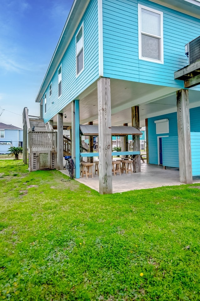 back of property with a lawn and a patio