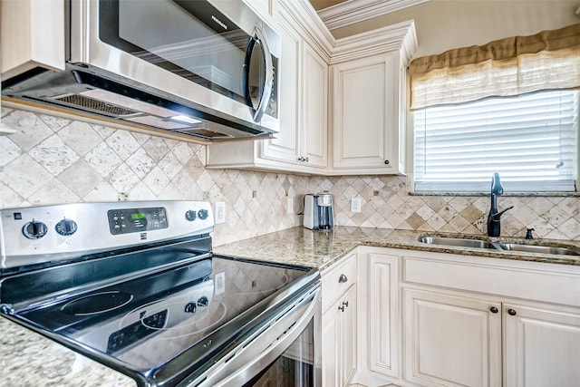 kitchen featuring backsplash, appliances with stainless steel finishes, light stone counters, and sink