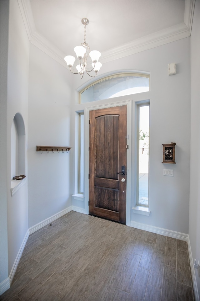 foyer featuring dark hardwood / wood-style floors, ornamental molding, a notable chandelier, and a healthy amount of sunlight