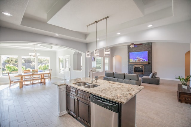 kitchen featuring sink, a raised ceiling, hanging light fixtures, dishwasher, and a fireplace