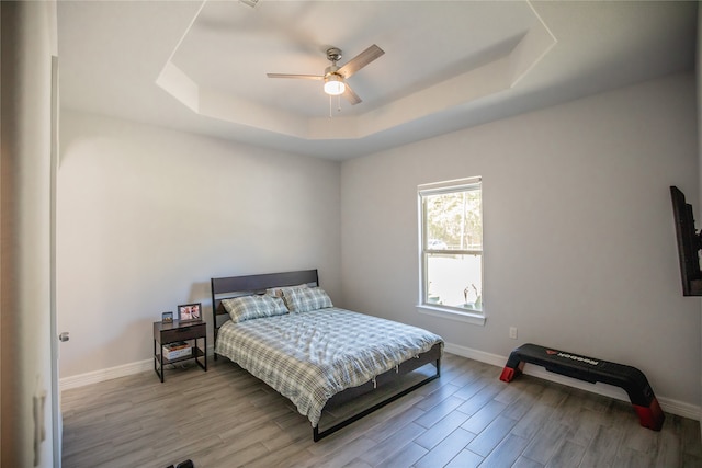 bedroom featuring ceiling fan, light hardwood / wood-style flooring, and a raised ceiling