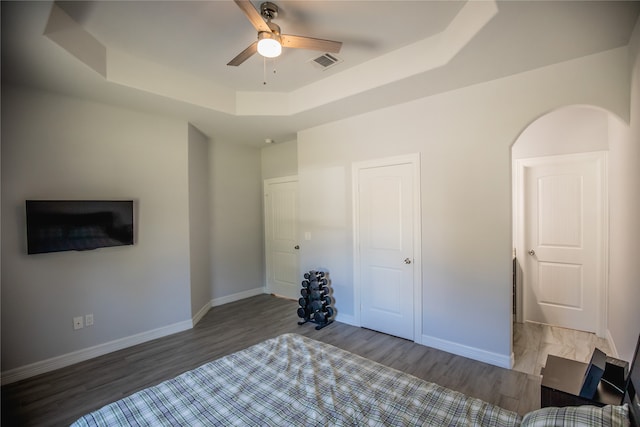 bedroom featuring ceiling fan, dark wood-type flooring, and a raised ceiling