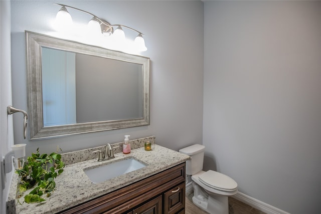 bathroom with toilet, hardwood / wood-style floors, and vanity