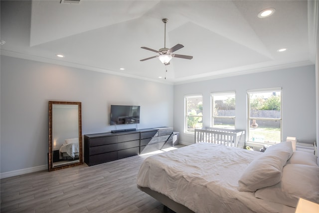 bedroom featuring ceiling fan, ornamental molding, hardwood / wood-style floors, and a tray ceiling