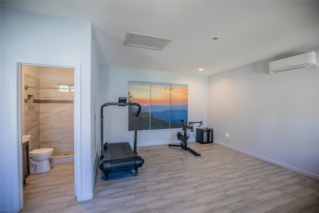 workout room with a wall mounted AC and light hardwood / wood-style floors