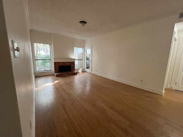 unfurnished living room featuring a textured ceiling, hardwood / wood-style flooring, and ornamental molding