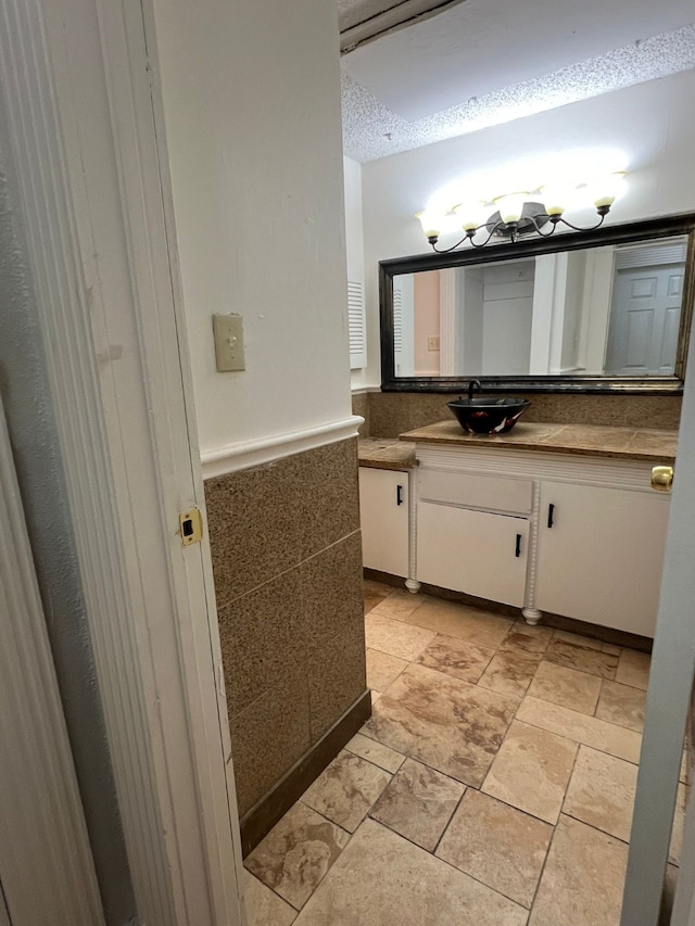 bathroom with tile flooring, vanity, and a textured ceiling