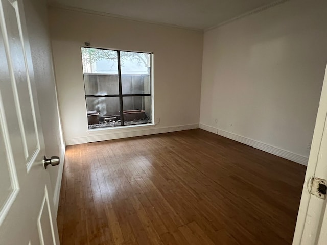 empty room featuring ornamental molding and dark hardwood / wood-style floors