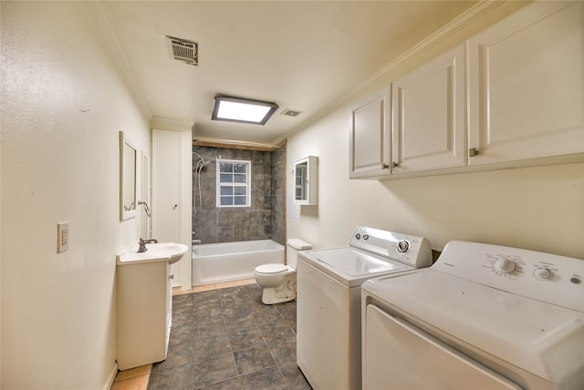 washroom with dark tile floors, washing machine and clothes dryer, ornamental molding, and sink