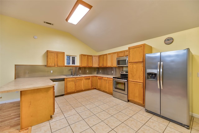 kitchen featuring vaulted ceiling, light hardwood / wood-style floors, stainless steel appliances, and kitchen peninsula