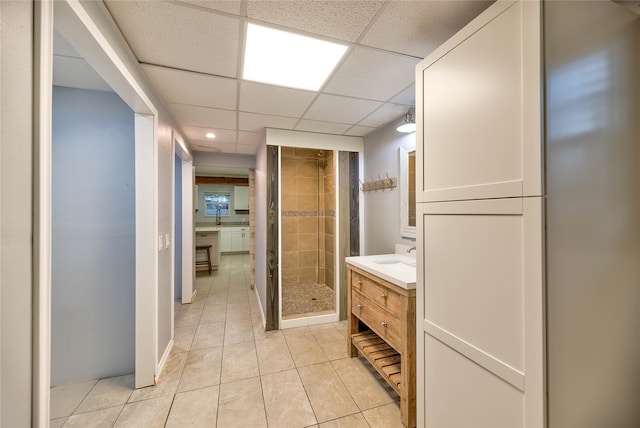 bathroom with vanity, tile flooring, a tile shower, and a drop ceiling