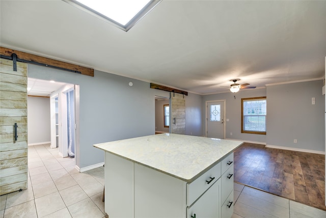 kitchen featuring a barn door, light tile flooring, a center island, and ceiling fan