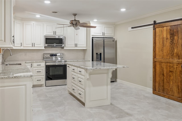 kitchen featuring a barn door, ceiling fan, tasteful backsplash, appliances with stainless steel finishes, and white cabinets