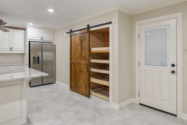 kitchen with light tile flooring, ceiling fan, a barn door, stainless steel refrigerator with ice dispenser, and white cabinets