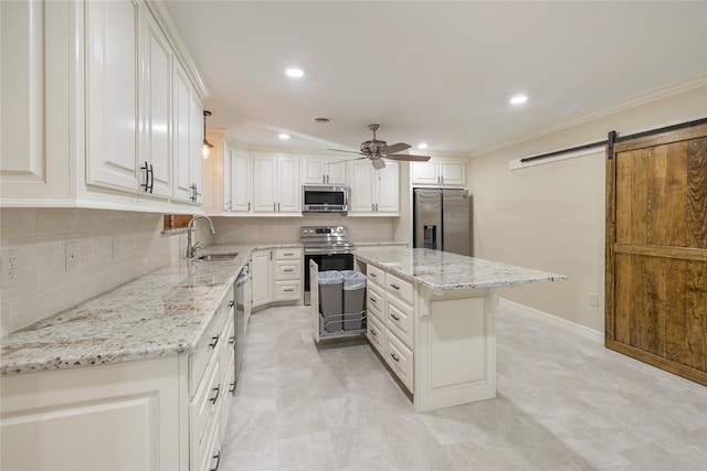 kitchen featuring stainless steel appliances, a barn door, ceiling fan, white cabinets, and sink