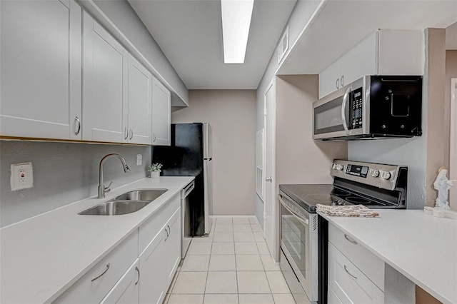 kitchen with appliances with stainless steel finishes, sink, light tile floors, and white cabinets