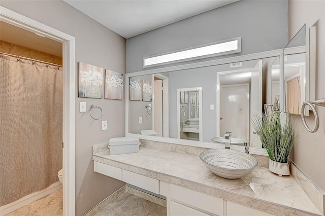 bathroom with tile flooring, toilet, and vanity