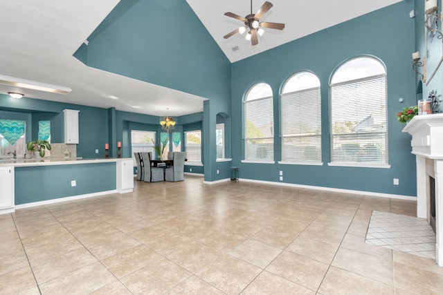 unfurnished living room featuring high vaulted ceiling, ceiling fan with notable chandelier, and light tile floors