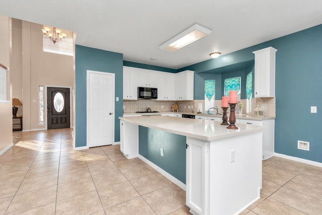 kitchen featuring light tile flooring, a center island, a notable chandelier, and white cabinetry