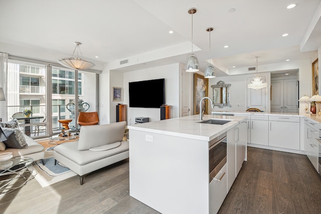 kitchen with hardwood / wood-style floors, sink, an island with sink, white cabinets, and pendant lighting