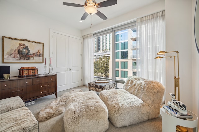 living area with light carpet and ceiling fan