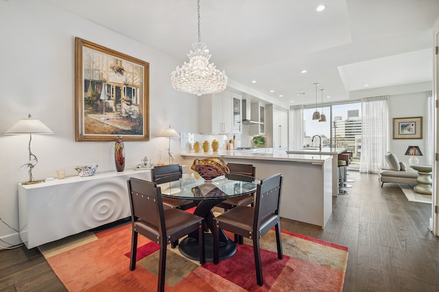 dining area featuring an inviting chandelier, light hardwood / wood-style flooring, sink, and a raised ceiling