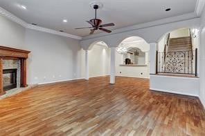 unfurnished living room featuring ornate columns, ceiling fan, hardwood / wood-style flooring, and ornamental molding