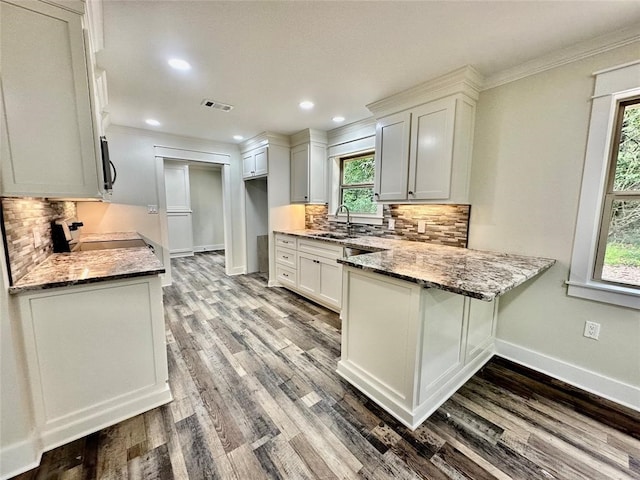 kitchen featuring light wood-type flooring, stone countertops, white cabinets, backsplash, and range