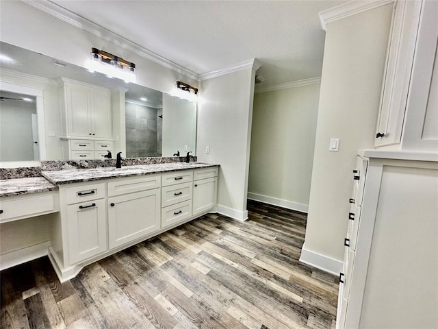 bathroom featuring wood-type flooring, dual sinks, ornamental molding, and vanity with extensive cabinet space