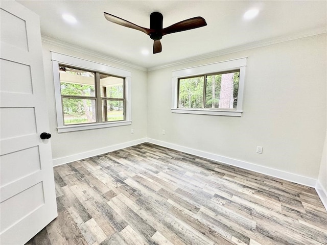 spare room featuring plenty of natural light, crown molding, ceiling fan, and light wood-type flooring