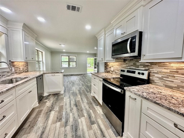 kitchen with backsplash, white cabinetry, appliances with stainless steel finishes, and light hardwood / wood-style floors