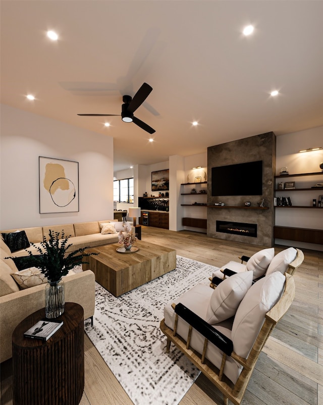 living room with built in features, ceiling fan, light wood-type flooring, and a fireplace