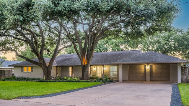 single story home featuring a garage and a yard